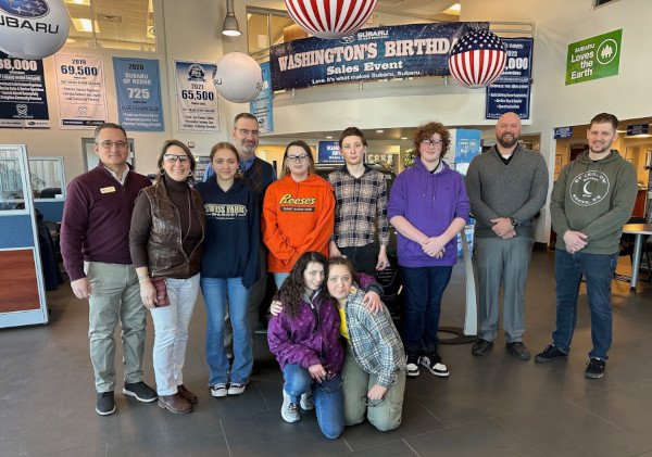 A group of people in a car dealership smiling.