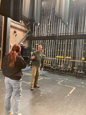 A man talking to a woman in the backstage area of a theater.