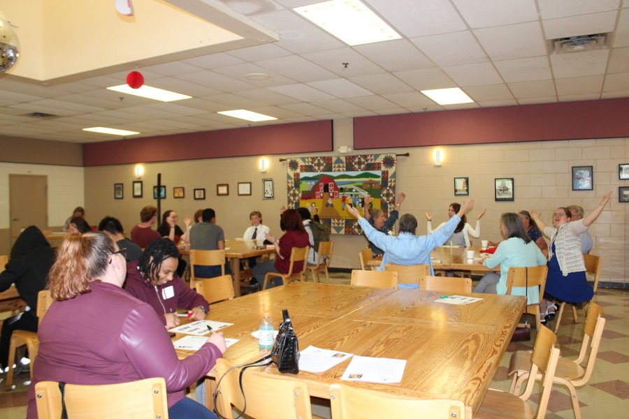 A room full of people seated at wooden tables.