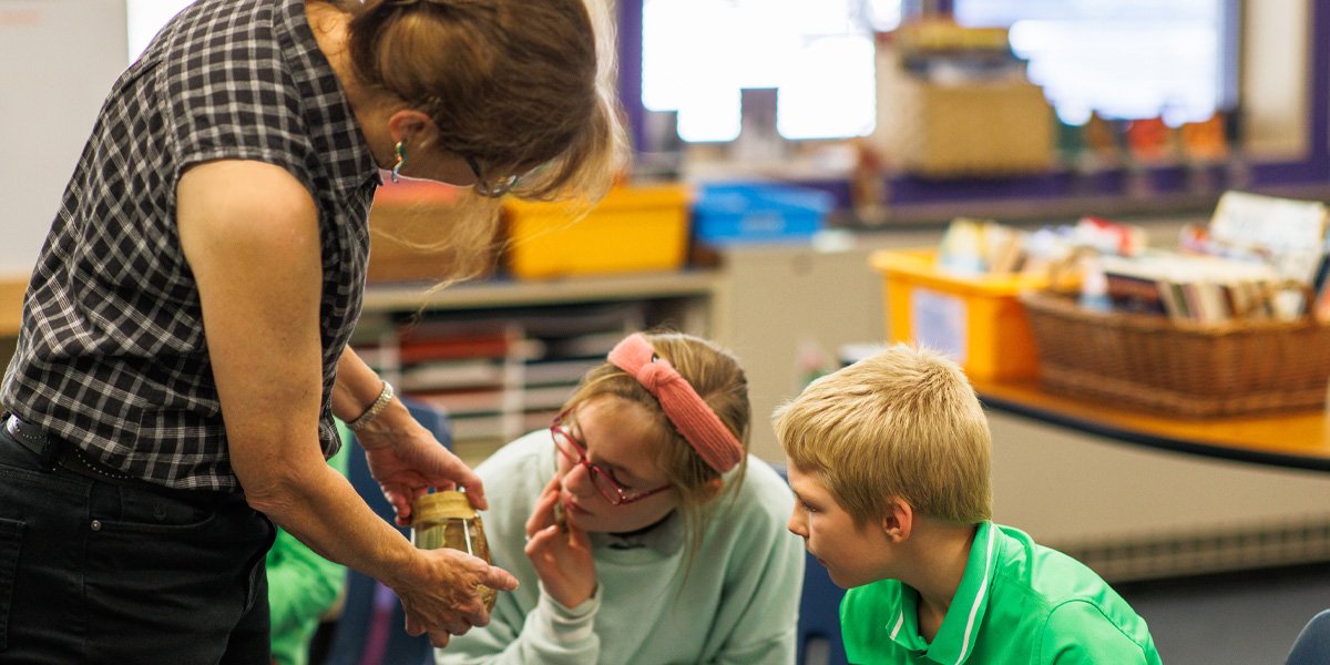 Teacher showing students a creature in a bottle