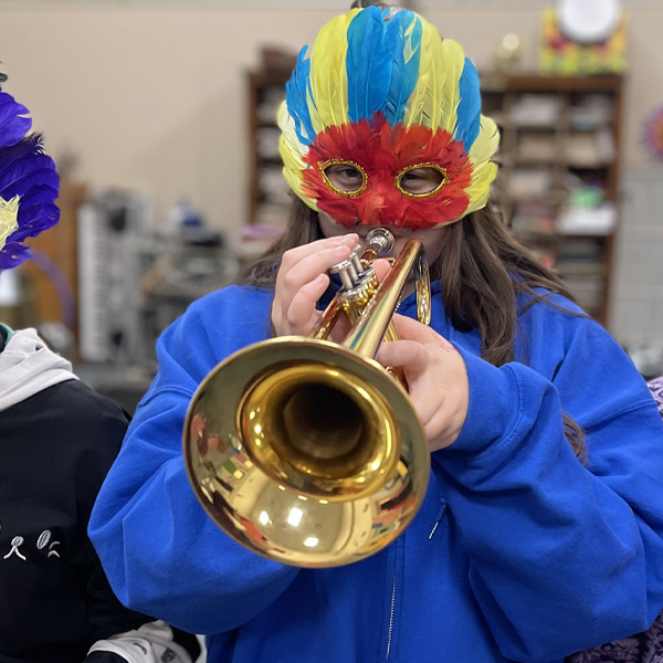 Student in halloween mask playing a trumpet