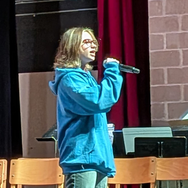 Student singing with microphone on stage